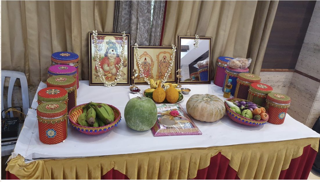 Angumaniseer laid on a table with decorated drums, deity pictures, fruit, and vegetables.